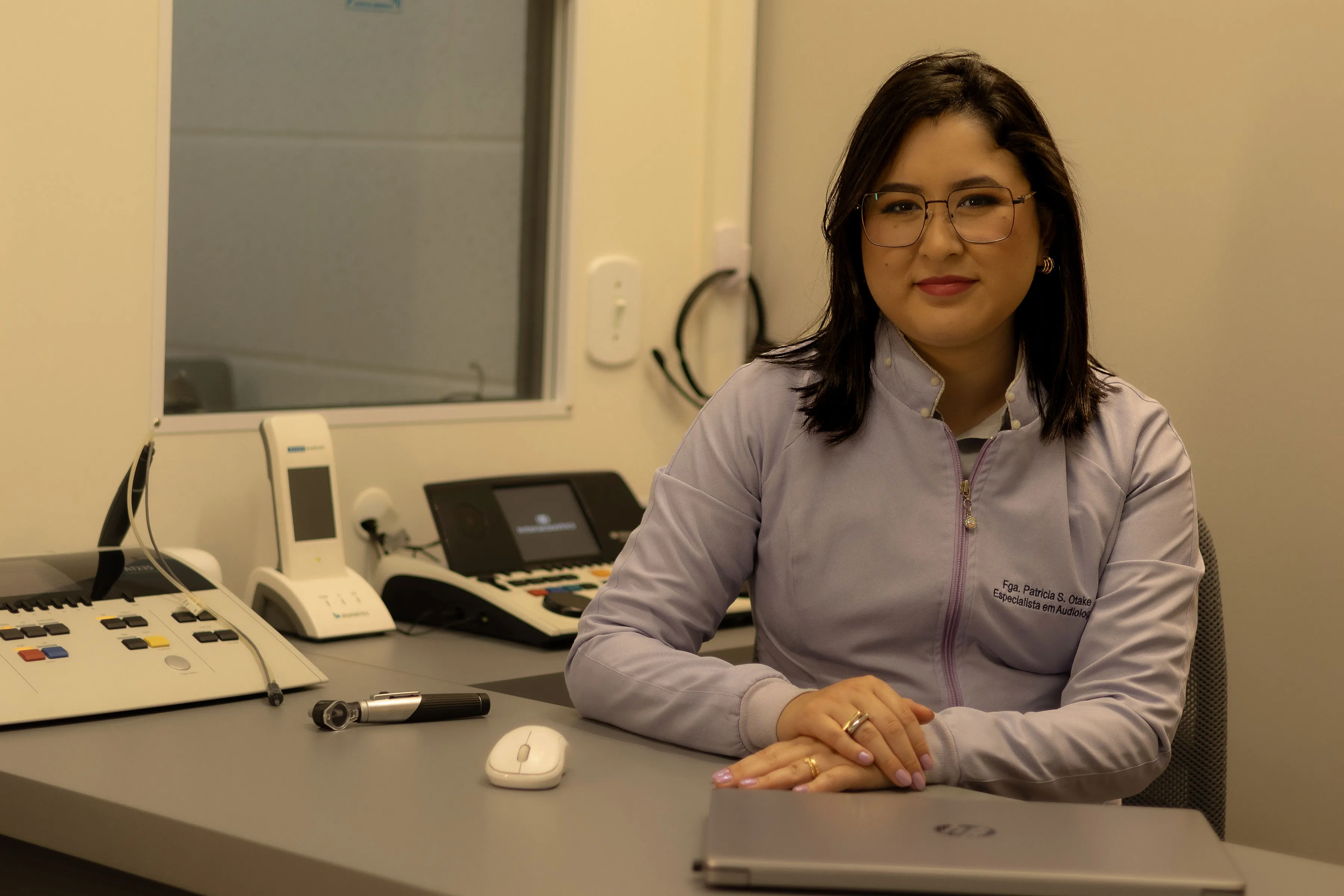 Patricia sem sua mesa ao lado dos aparelhos utilizados nos exames